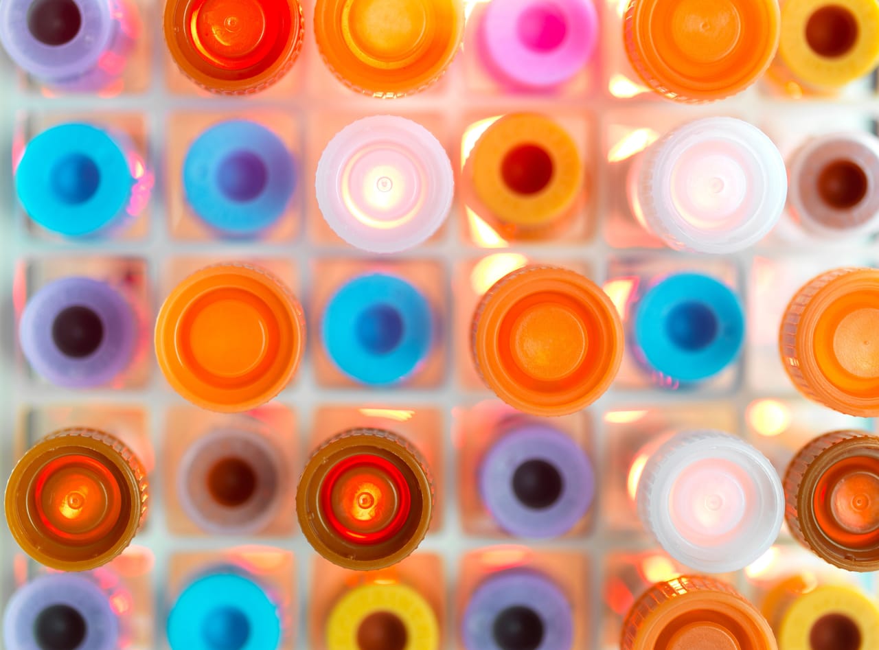 Colorful plastic caps of various laboratory vials or test tubes arranged in a grid.